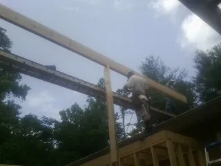 Carpenter setting a ridge beam over a new addition frame — Ice Dam Removal by Roofing Brothers in Rural Valley