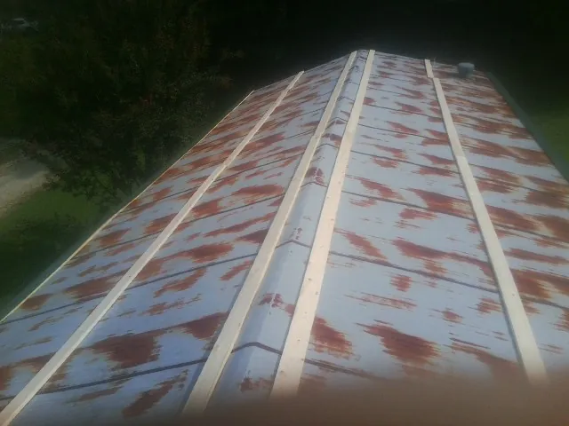 Rusted metal roof panels with new wood purlins before replacement — Storm Damage Roof Repair in Rural Valley by Roofing Brothers