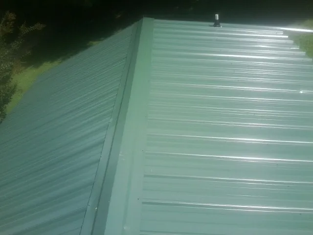 New green metal panels meeting at the ridge of a roof — Flat Roof Repair work by our crew in Rural Valley