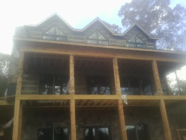 Dormers and porch framing on a large log home under construction — Roof Coating work by our crew in Rural Valley