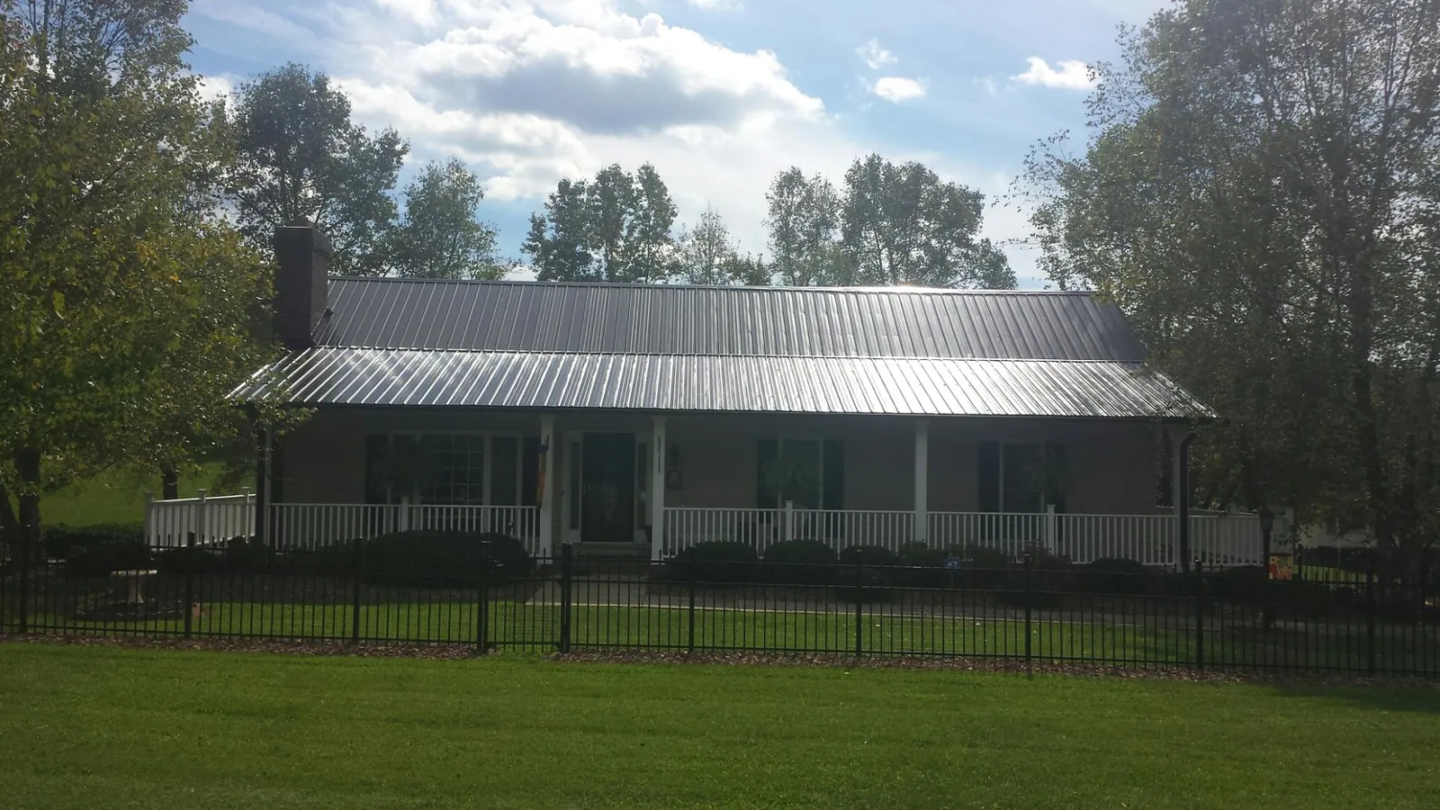 Gray metal roof on a brick ranch with a full width front porch — Gutter Guard Installation work by our crew in Rural Valley