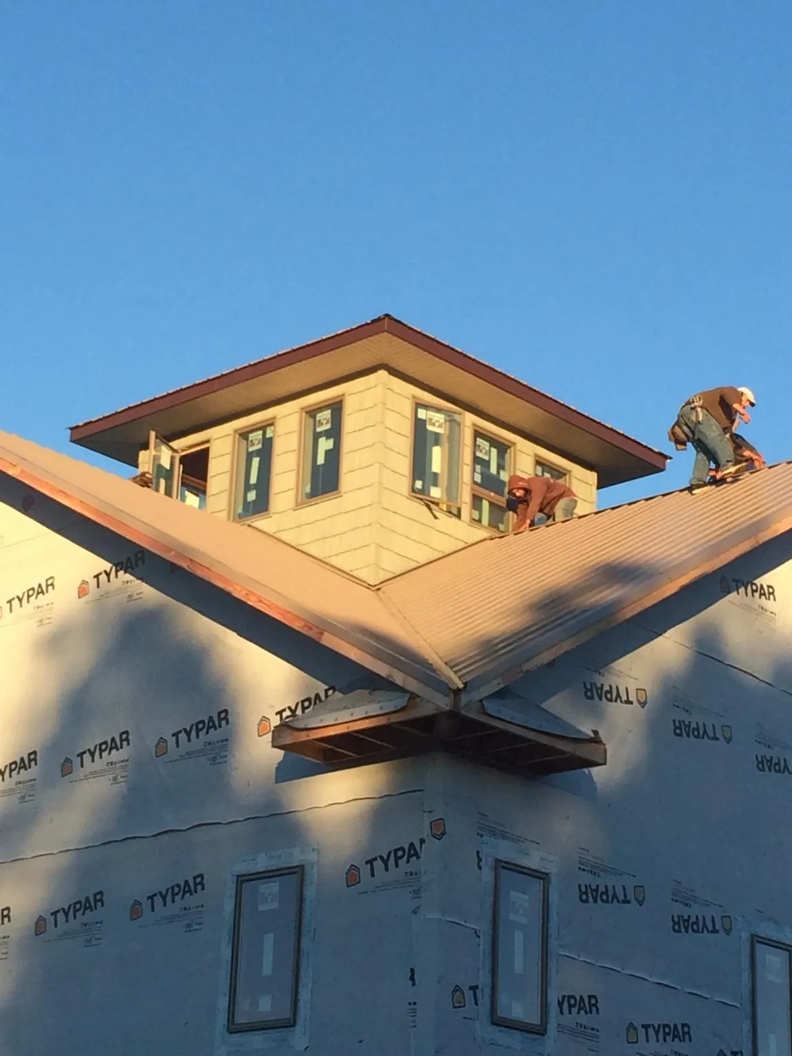 Roofers working around a rooftop cupola on a new metal roof at sunset — Roof Waterproofing in Rural Valley by Roofing Brothers